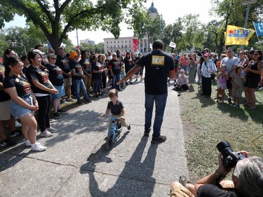A youngster rides past NDP provincial party leader Wab Kinew as he speaks at Memorial Park ahead of the Labour Day March in Winnipeg on Monday, Sept. 5, 2022.