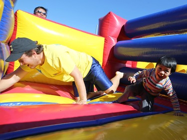 A boy is lead through a bouncy castle as his father looks on at the ManyFest street festival in downtown Winnipeg on Sunday, Sept. 11, 2022, which returned after a two-year absence due to COVID-19.