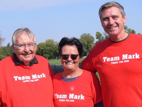 (Left to right) Bob Adkins, his wife Nancy Adkins and youngest son Matthew Adkins pose in their red Team Mark t-shirts at the 2022 Terry Fox Run at Assiniboine Park in Winnipeg. The Adkins have taken part in Terry Fox Runs since 2018 after their eldest son Mark passed away from pancreatic cancer. This year, Team Mark raised $13,150 for cancer research.
