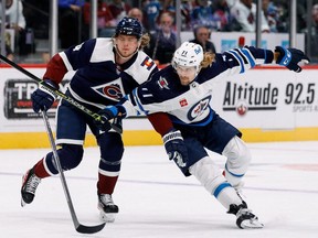 Winnipeg Jets left winger Axel Jonsson-Fjallby (right) and Colorado Avalanche defenceman Bowen Byram battle for the puck in the first period at Ball Arena in Denver on Oct. 19, 2022.