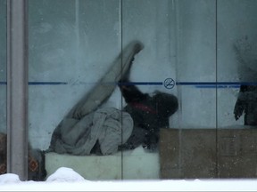A person adjusts their covers in a bus shelter