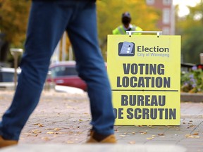 A person walks by an election sign at City Hall in Winnipeg, one of the advance polling stations which closed on Friday.
