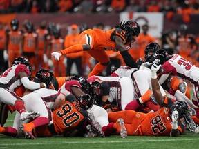B.C. Lions' Jordan Williams (21) leaps on top of the pile as Ottawa Redblacks quarterback Caleb Evans, centre right, pushes ahead for a first down during the first half of CFL football game in Vancouver, on Friday, September 30, 2022.