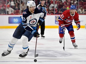 Sep 29, 2022; Montreal, Quebec, CAN; Winnipeg Jets defenseman Johnathan Kovacevic (65) moves the puck ahead of Montreal Canadiens forward Evgenii Dadonov (63) during the second period at the Bell Centre. Mandatory Credit: Eric Bolte-USA TODAY Sports