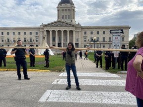 A protester carries a pole away from an encampment on the front lawn of the Manitoba legislature, in Winnipeg, Monday, Oct. 3, 2022. Winnipeg police stopped protesters from bringing in poles for a new teepee that would have expanded the encampment, which has been in place for several months.