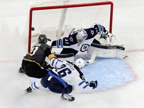 The puck hits a goal post as Connor Hellebuyck #37 and Blake Wheeler #26 of the Winnipeg Jets defends the net against Brett Howden #21 of the Vegas Golden Knights in the first period of their game at T-Mobile Arena on October 30, 2022 in Las Vegas, Nevada. The Golden Knights defeated the Jets 2-1 in overtime.