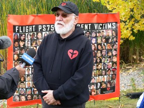 Kourosh Doustshenas, Association of Families of Flight PS752 Victims, is interviewed at a tree-planting at Scurfield Park in Whyte Ridge in Winnipeg on Saturday, Oct. 1, 2022, in memory of the victims of Flight PS752 which was shot down by missiles only minutes after takeoff from Tehran's IKA airport, killing all 176 passengers and crew on board including 63 Canadians. Behind him is a poster including faces of the Winnipeg victims of the flight.