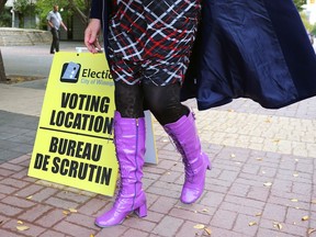 A person walks by an election sign at City Hall in Winnipeg, one of the advance polling stations which opened on Monday, Oct. 3, 2022.