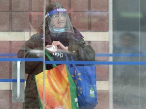 A person wears a face shield while at a bus stop in Winnipeg on Tuesday.  Chris Procaylo/Winnipeg Sun