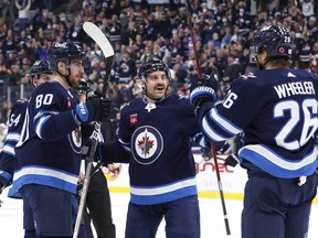 Winnipeg Jets defenceman Dylan DeMelo (2) and right winger Blake Wheeler (26) celebrate the second-period goal by Pierre-Luc Dubois (80) against the Dallas Stars.