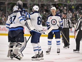 Winnipeg Jets defenceman Nate Schmidt (88) and goaltender Connor Hellebuyck (37) and defenceman Brenden Dillon (5) celebrate the victory over the Dallas Stars during the overtime period at the American Airlines Center in Dallas on Friday, Nov. 25, 2022.