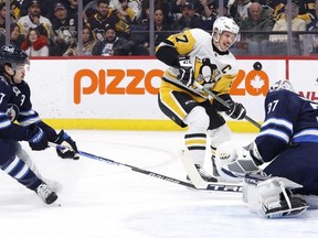 Jets goaltender Connor Hellebuyck blocks a shot by Pittsburgh Penguins centre Sidney Crosby as Winnipeg centre Adam Lowry looks for a rebound at Canada Life Centre last night. The Jets lost to the Penguins 3-0.   USA TODAY SPORTS