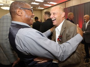 Mike Riley (right) and Rod Hill of the 1990 Winnipeg Blue Bombers say hello ahead of its induction into the Manitoba Sports Hall of Fame during a ceremony at the Victoria Inn in Winnipeg on Thursday, Nov. 3, 2022.