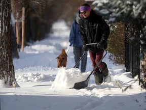 A person clears snow from a sidewalk in Winnipeg on Friday, Nov. 11, 2022.