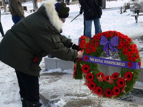 A woman pins a poppy to one of the wreaths at the Rifles regimental pillar at Vimy Ridge Memorial Park in Winnipeg for Remembrance Day ceremonies on Friday, Nov. 11, 2022. The pillar contains the names of soldiers from the Rifles who served during the Second World War. This year's Remembrance Day ceremonies saw a return to normal after two years of pandemic-related restrictions forced scaled-down commemorations.