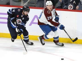 Colorado Avalanche centre Nathan MacKinnon (right) makes a backhand pass with Winnipeg Jets defenceman Josh Morrissey defending in Winnipeg on Tuesday, Nov. 29, 2022.