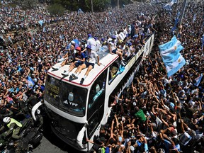 TOPSHOT - Fans of Argentina cheer as the team parades on board a bus after winning the Qatar 2022 World Cup tournament in Buenos Aires, Argentina on December 20, 2022. - Millions of ecstatic fans are expected to cheer on their heroes as Argentina's World Cup winners led by captain Lionel Messi began their open-top bus parade of the capital Buenos Aires on Tuesday following their sensational victory over France. (Photo by Luis ROBAYO / AFP) (Photo by LUIS ROBAYO/AFP via Getty Images)