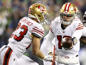 49ers QB Brock Purdy, right, hands the ball off to Christian McCaffrey, left, during third quarter NFL action against the Seahawks at Lumen Field in Seattle, Thursday, Dec. 15, 2022.