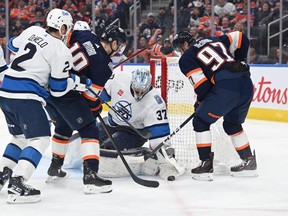 Winnipeg Jets defenceman Dylan DeMelo (2) and Edmonton Oilers left winger Zach Hyman (18) and Oilers centre Connor McDavid (97) battle in front of Jets goalie Connoer Hellebuyck (37) during the third period at Rogers Place in Edmonton on Saturday, Dec. 31, 2022. Winnipeg won 2-1.