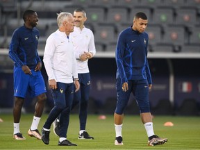 France's coach Didier Deschamps (C) speaks with France's forward #10 Kylian Mbappe during a training session at the Al Sadd SC training centre in Doha on December 17, 2022, on the eve of the Qatar 2022 World Cup football final match between Argentina and France.