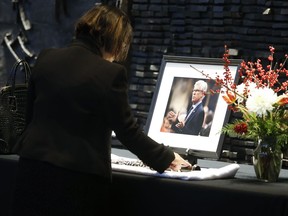 A woman touches an oboe in front of a portrait at a memorial service for Member of Parliament Jim Carr at the Centennial Concert Hall in Winnipeg, Saturday, Dec. 17, 2022. Carr died last week of cancer.