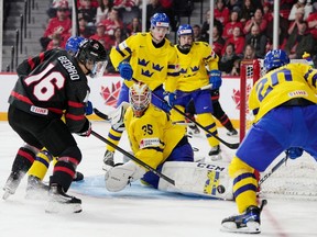 Sweden's goaltender Carl Lindbom, centre, makes a pad save on Canada's Connor Bedard, left, during second period IIHF World Junior Hockey Championship action in Halifax, Saturday, Dec. 31, 2022.