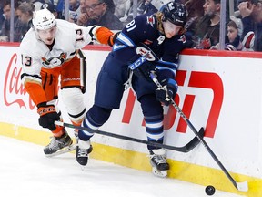 Anaheim Ducks defenseman Simon Benoit (13) checks Winnipeg Jets left wing Kyle Connor (81) in the second period at Canada Life Centre in Winnipeg on Sunday, Dec. 4, 2022.