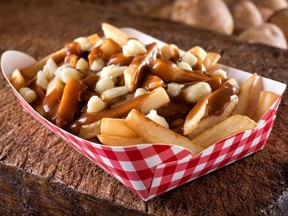 A serving of delicious poutine with french fries, cheese curds.