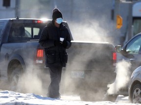 A person begs from passing motorists near a homeless shelter, in Winnipeg on Tuesday, Jan. 26, 2021.