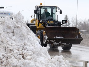 A front end loader drives past a large pile of snow left by a recent storm, in Winnipeg on Wednesday, April 14, 2021.