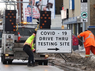 City workers remove signage for the drive-through COVID-19 testing site on Main Street in Winnipeg on Mon., March 21, 2022 as the province wound down most of its public health restrictions.