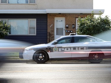 Traffic goes past a cruiser sitting in front of a duplex on Logan Avenue near McPhillips Street in Winnipeg, where a person was shot in the leg during a home invasion on Mon., Sept. 5, 2022.