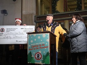 Manitoba Metis Federation President David Chartrand presents a cheque for $50,000 to Winnipeg Christmas Cheer Board Executive Director Shawna Bell (right) as the MMF kicked off the holiday season by lighting up the future home of their heritage centre, located at the iconic corner of Portage and Main in Winnipeg.on Friday, Dec. 9, 2022. It is the charity's largest public donation of the year.