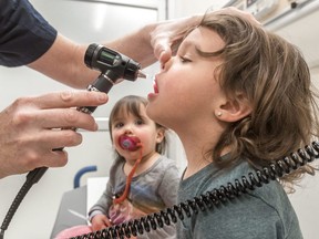 A doctor checks a child for the flu.