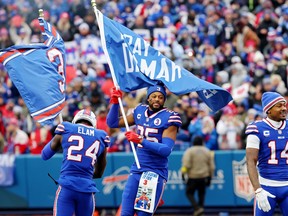 Kaiir Elam and Taiwan Jones of the Buffalo Bills wave flags in support of teammate Damar Hamlin at Highmark Stadium prior to a game against the New England Patriots on January 08, 2023 in Orchard Park, New York.
