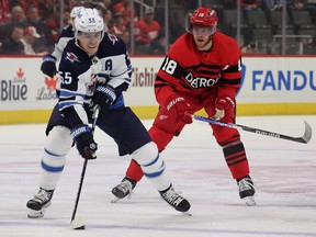 Mark Scheifele (55) of the Winnipeg Jets tries to control the puck in front of Andrew Copp (18) of the Detroit Red Wings during the first period at Little Caesars Arena on Jan. 10, 2023 in Detroit.