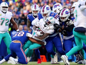 Matt Milano #58 and Eli Ankou #51 of the Buffalo Bills tackles Jeff Wilson Jr. #23 of the Miami Dolphins during the second half of the game in the AFC wild card playoff game at Highmark Stadium on January 15, 2023 in Orchard Park, New York.