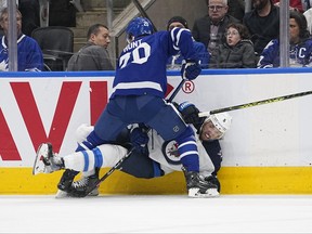 Maple Leafs forward Dryden Hunt (left) hits Jets defenceman Brenden Dillon along the boards during the second period at Scotiabank Arena in Toronto Thursday night.