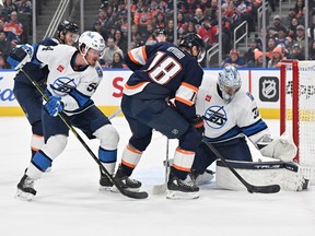 Edmonton Oilers left wing Zach Hyman (18) shoots on Winnipeg Jets goalie Connor Hellebuyck (37) and defenceman Dylan Samberg (54) during the first period at Rogers Place in Edmonton on Saturday, Dec. 31, 2022.