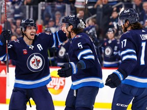 Winnipeg Jets defenseman Brenden Dillon (5) celebrates his goal in the second period with center Mark Scheifele (55) and center Adam Lowry (17) against the Calgary Flames at Canada Life Centre in Winnipeg on Tuesday, Jan. 3, 2023.