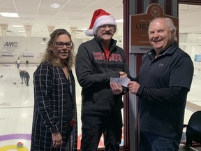 Assiniboine Memorial Curling Club's Al Seredynski (right) and club manager Jody Smart (left) present a cheque for $632.50 to Winnipeg Sun's Glen Dawkins for the Empty Stocking Fund and the Christmas Cheer Board at the Assiniboine Memorial Curling Club in Winnipeg on Tuesday, Jan. 3, 2023. Handout/Assiniboine Memorial Curling Club