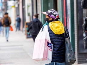 A woman wearing a mask and gloves carries a shopping bag during a phased reopening from the coronavirus restrictions in Toronto May 19, 2020.