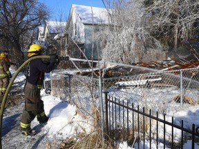 A firefighter hoses down hotspots at a property where the house was demolished after a fire on Stella Avenue in Winnipeg on Tues., Jan. 3, 2023.