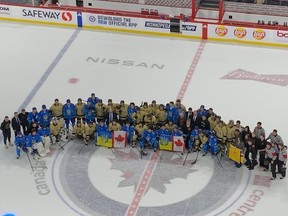 Des membres des Bisons de l'Université du Manitoba et de l'équipe nationale ukrainienne des moins de 25 ans se réunissent aux côtés d'officiels sur la glace au Canada Life Centre à Winnipeg après la victoire de 5-1 de l'Ukraine lors de la tournée Can't Stop Hockey le lundi 9 janvier 2023,