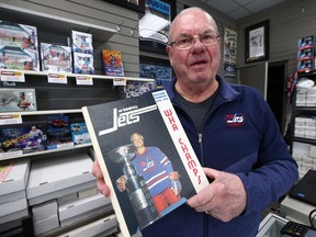 Joe Daley holds a book featuring former Winnipeg Jets teammate Bobby Hull at his sports shop on St. Mary's Road in Winnipeg on Monday, Jan. 30, 2023. The Golden Jet died Monday at age 84.