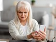 Suspicious, worried mature woman looking at smartphone