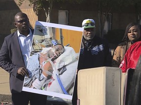 In this photo provided by WREG, Tyre Nichols' stepfather Rodney Wells, centre, stands next to a photo of Nichols in the hospital after his arrest, during a protest in Memphis, Tenn., Saturday, Jan. 14, 2023.