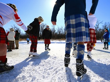 People wearing kilts step tentatively onto the ice for the Great Canadian Kilt Skate on the duck pond at Assiniboine Park in Winnipeg on Sunday, Feb. 26, 2023.