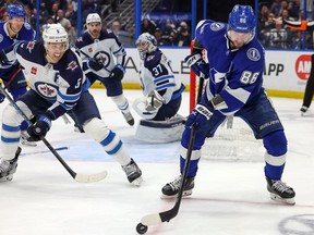 Nikita Kucherov (86) of the Tampa Bay Lightning looks to pass against the defense of Brenden Dillon (5) of the Winnipeg Jets during the second period of a hockey game at the Amalie Arena on Sunday, March 12, 2023 in Tampa, Fla.