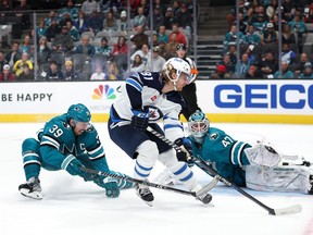 Logan Couture and James Reimer of the San Jose Sharks stop Kyle Connor #81 of the Winnipeg Jets from scoring in the third period  at SAP Center on March 28, 2023 in San Jose, California.